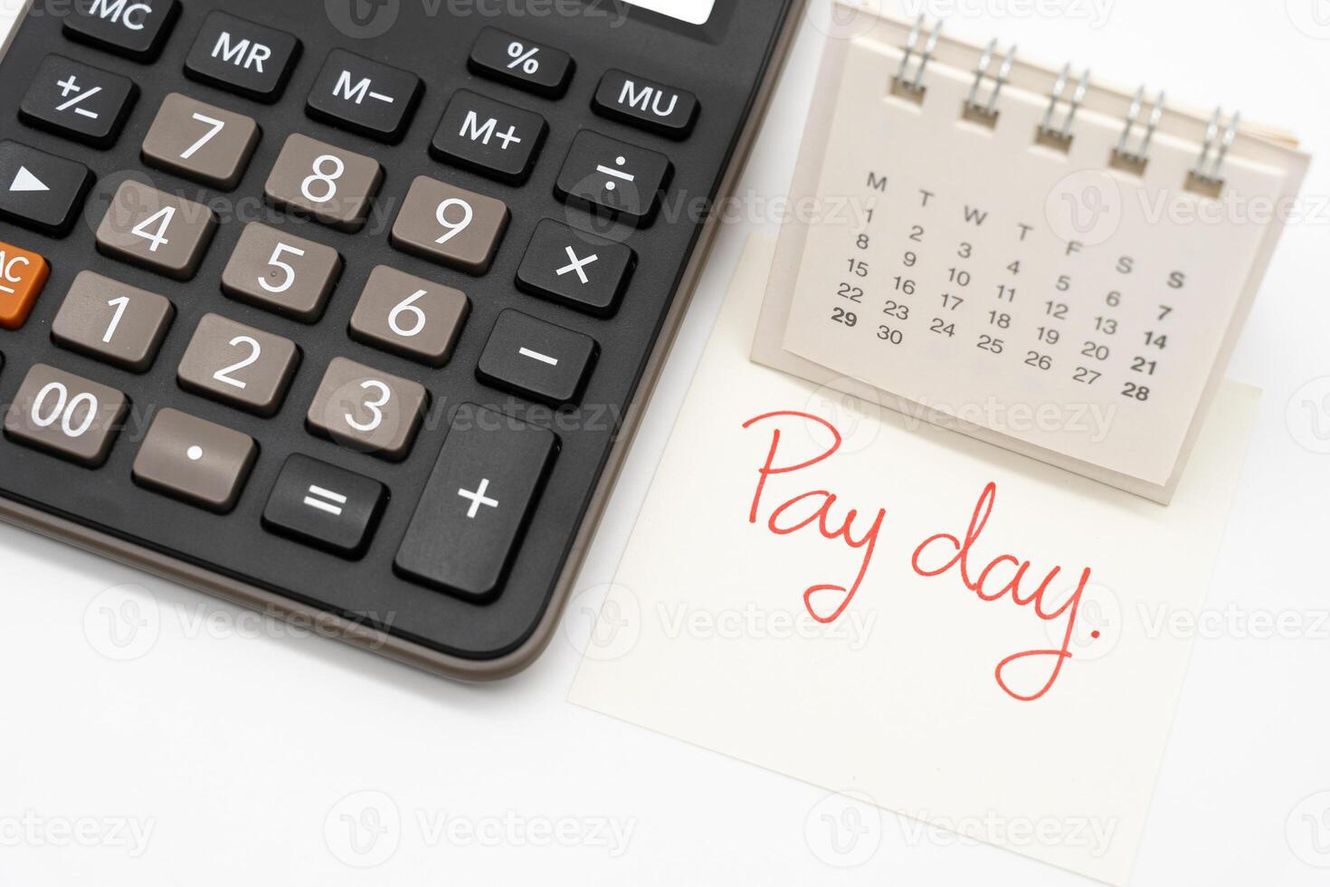 For payday concept. Desk calendar, calculator and paper note in isolated background. Business, finance, savings money, wages, payroll or accounting concept. photo