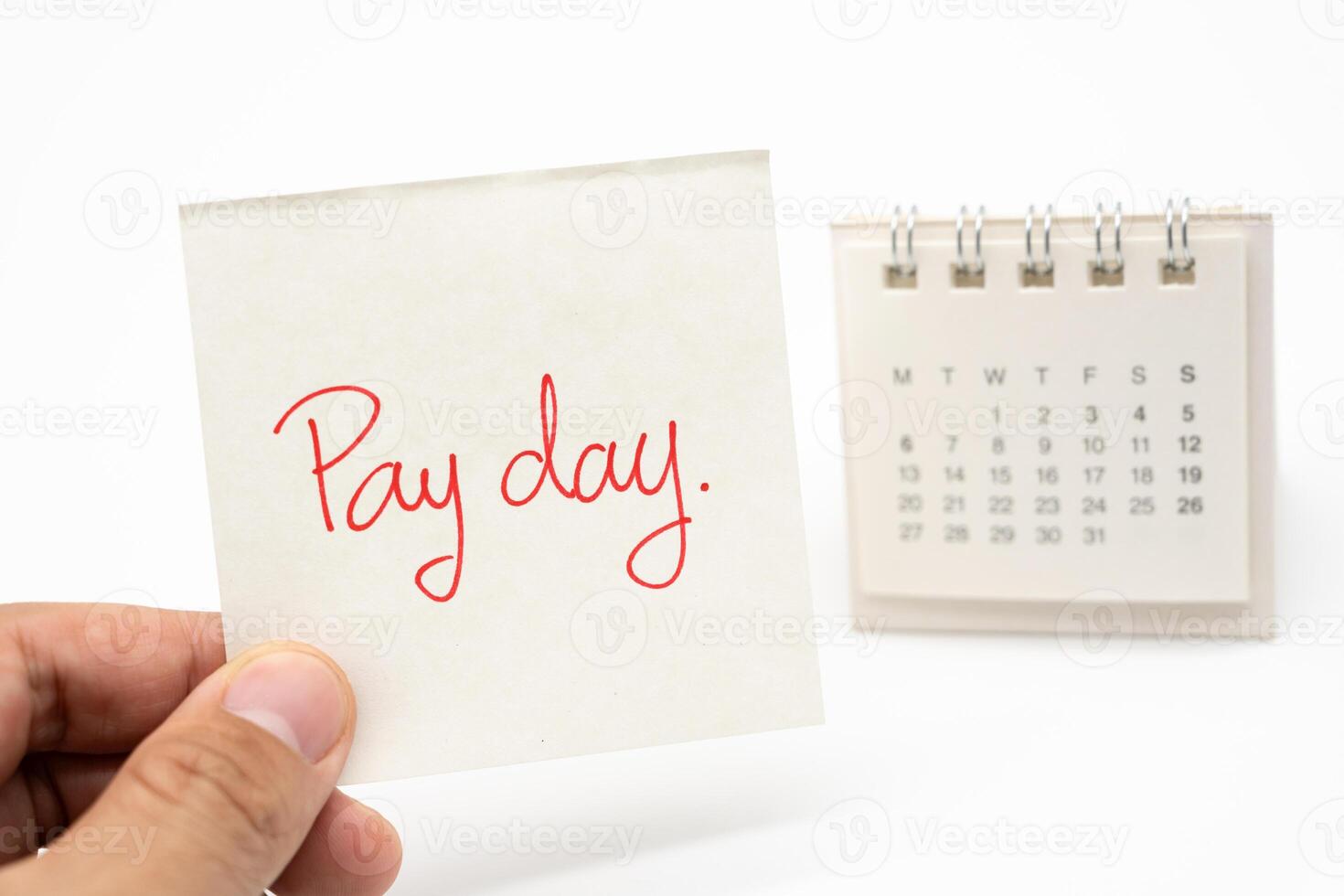 For payday concept. Desk calendar and paper note in isolated background. Business, finance, savings money, wages, payroll or accounting concept. photo