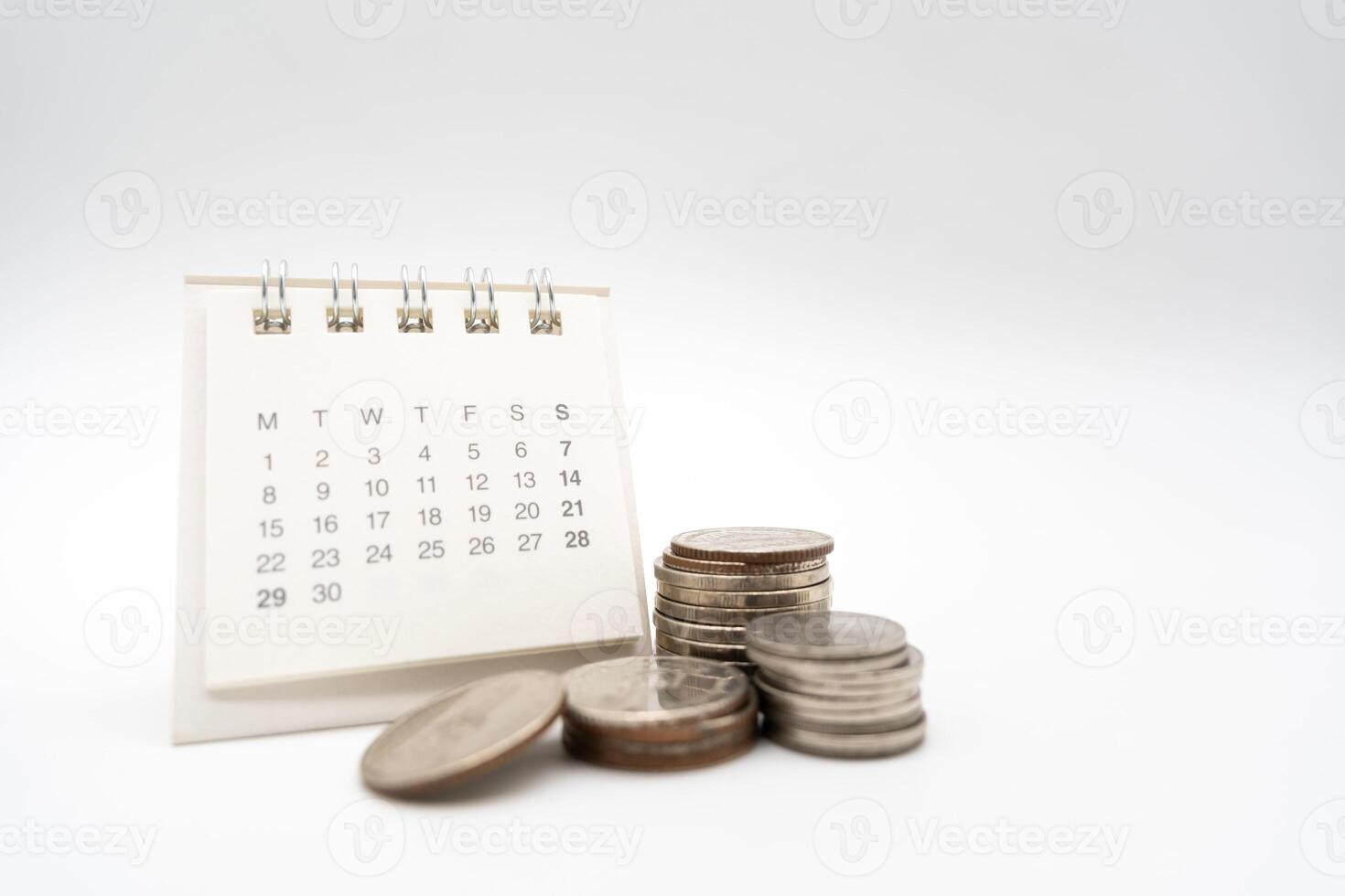 For payday loan concept. Desk calendar and blurred stack of coins in isolated background. Business, finance, savings money, wages, payroll or accounting concept photo