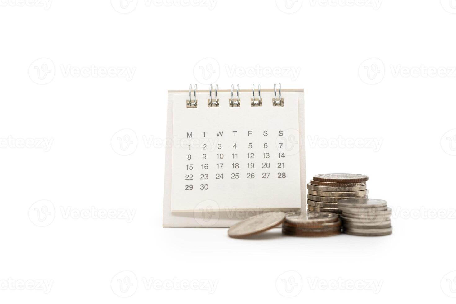 For payday loan concept. Desk calendar and blurred stack of coins in isolated background. Business, finance, savings money, wages, payroll or accounting concept photo