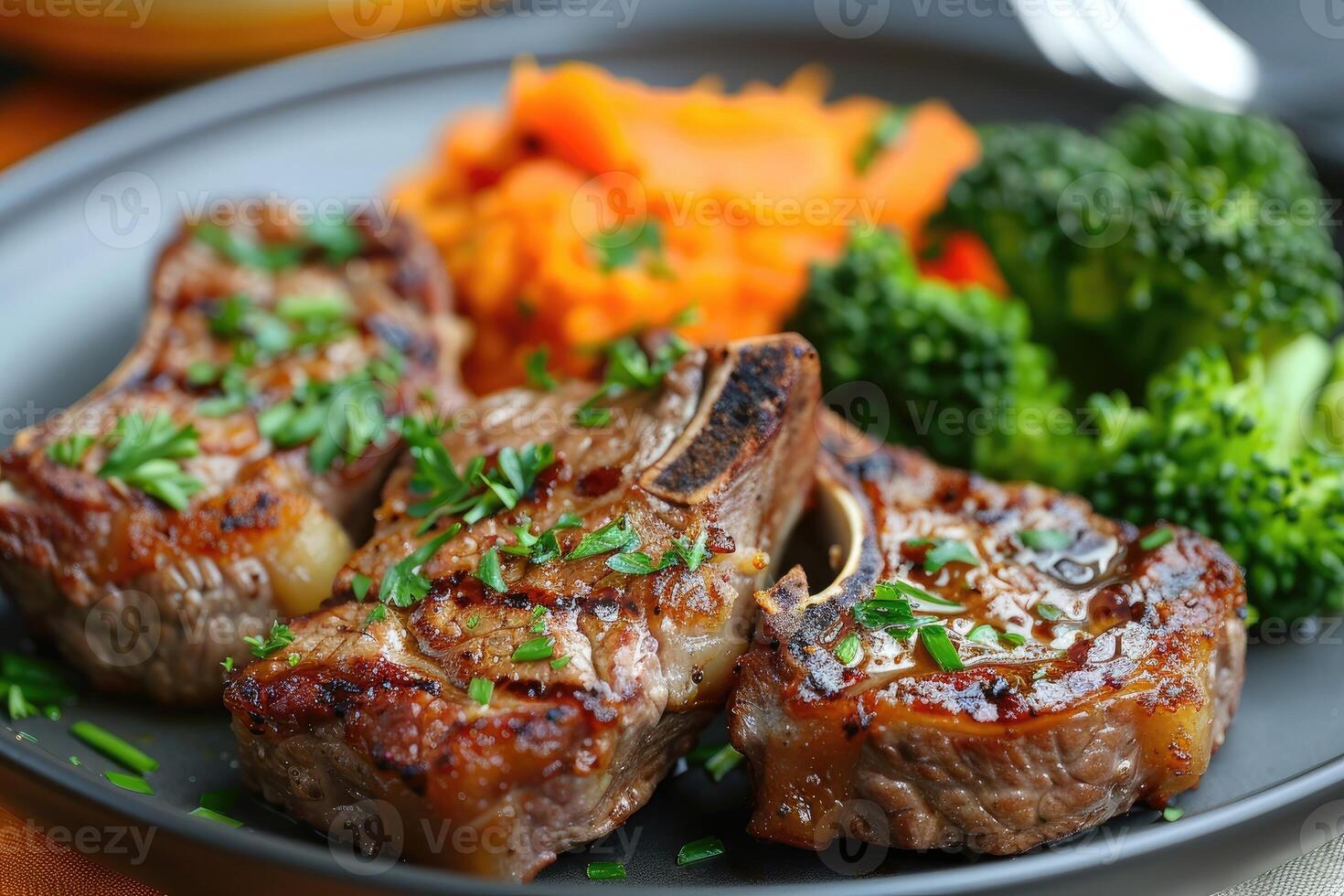 Roasted lamb chops with a side of mashed sweet potato and steamed vegetables. The steamed vegetables are a mix of broccoli and carrots. photo