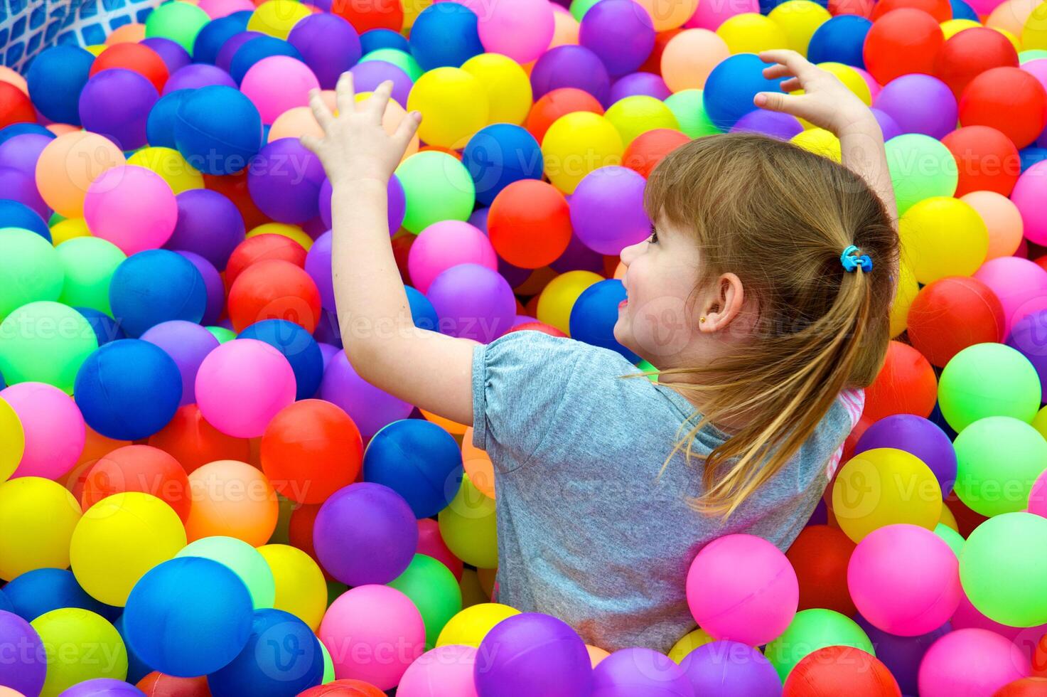 Girl playing on colourful balls photo