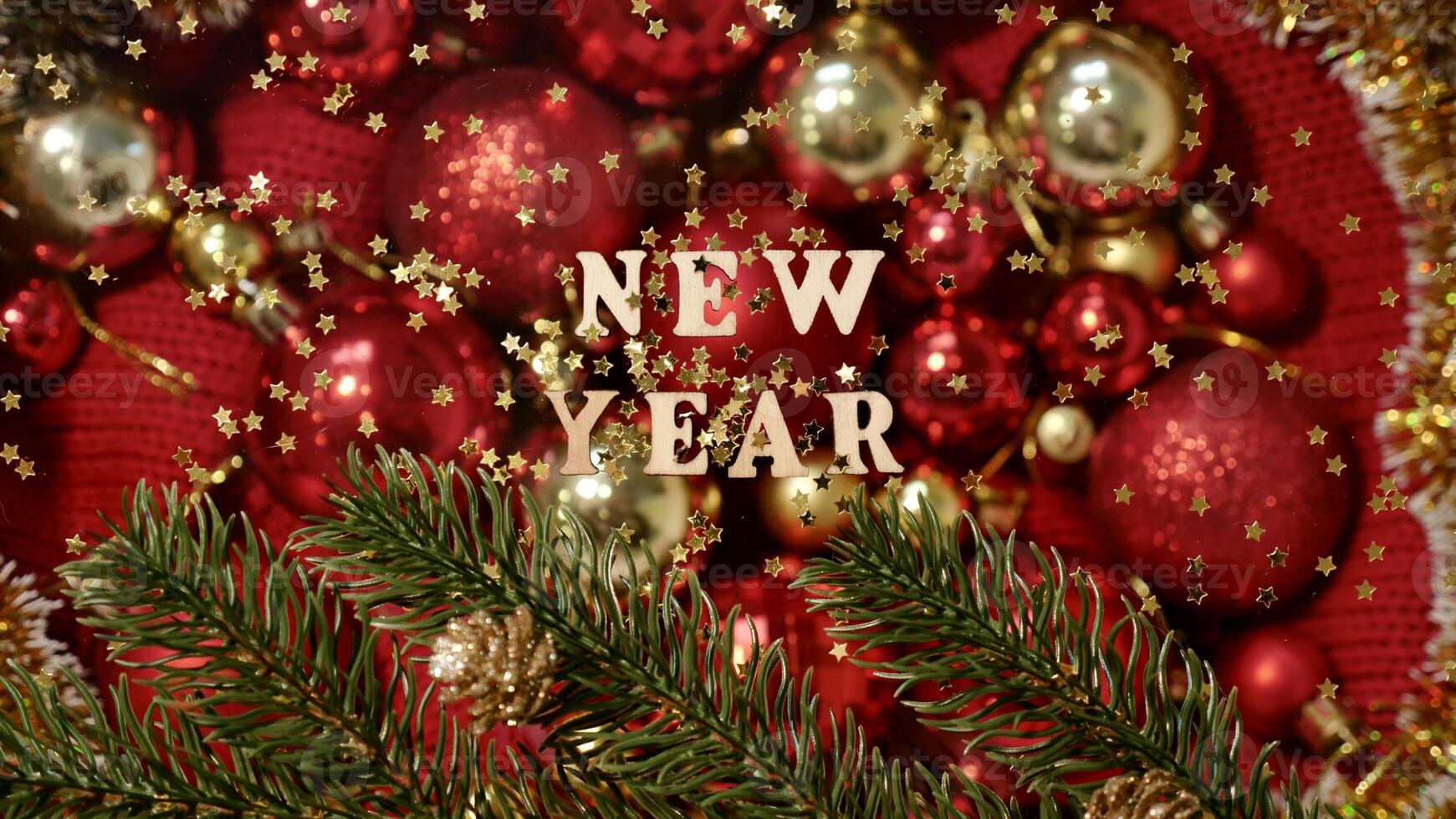 Christmas flatley with New Year lettering on blurred red gold background baubles decoration. Close-up, shiny composition. Postcard photo