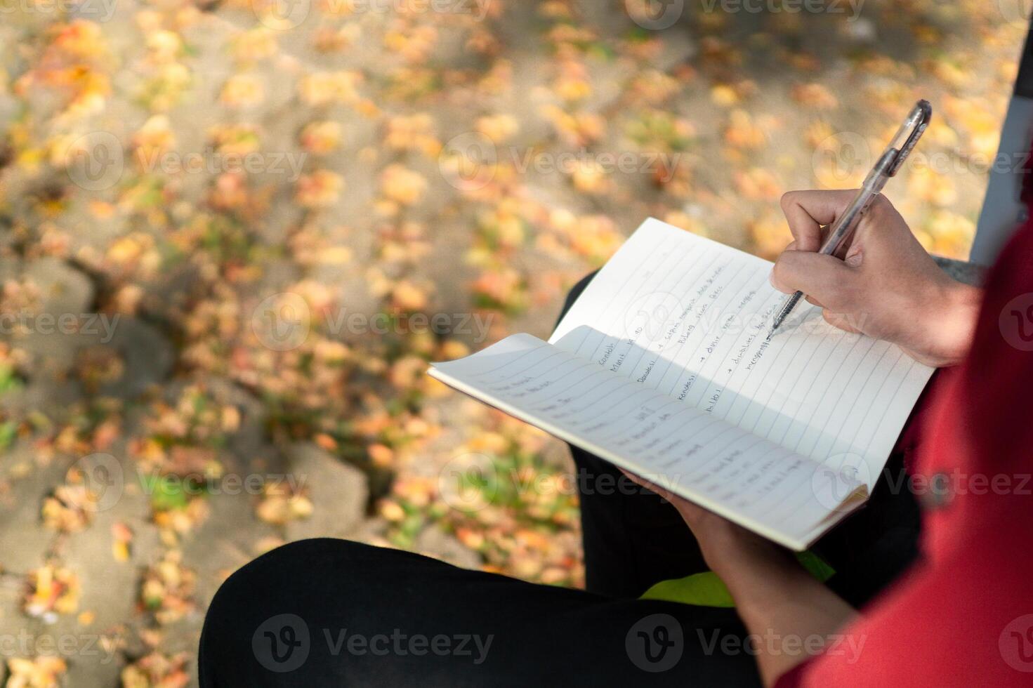 Asian college student studying on laptop at campus outdoor park. Man writing on a note book and working on laptop. Educational concept photo