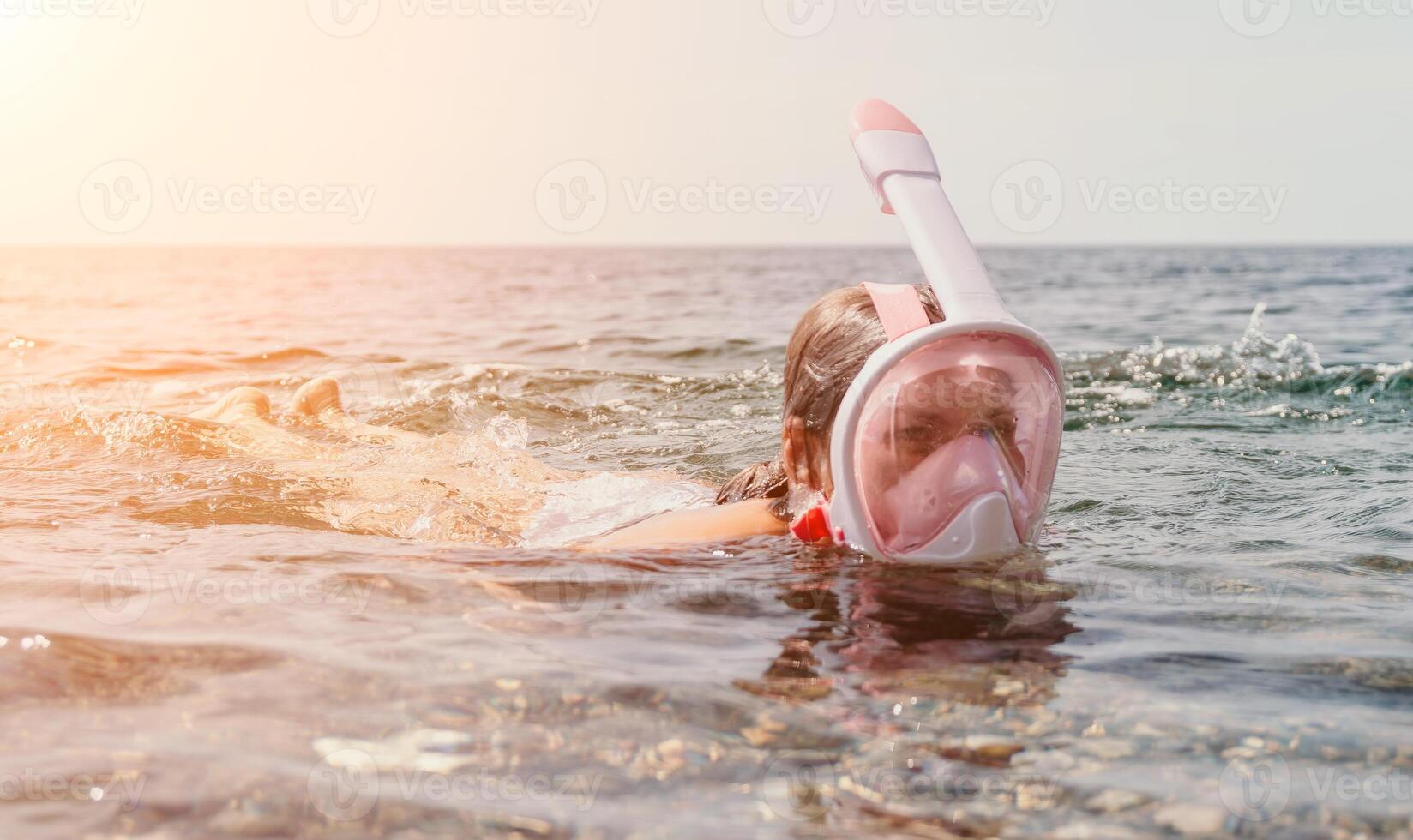 Young happy woman in white bikini and wearing pink mask gets ready for sea snorkeling. Positive smiling woman relaxing and enjoying water activities with family summer travel holidays vacation on sea. photo