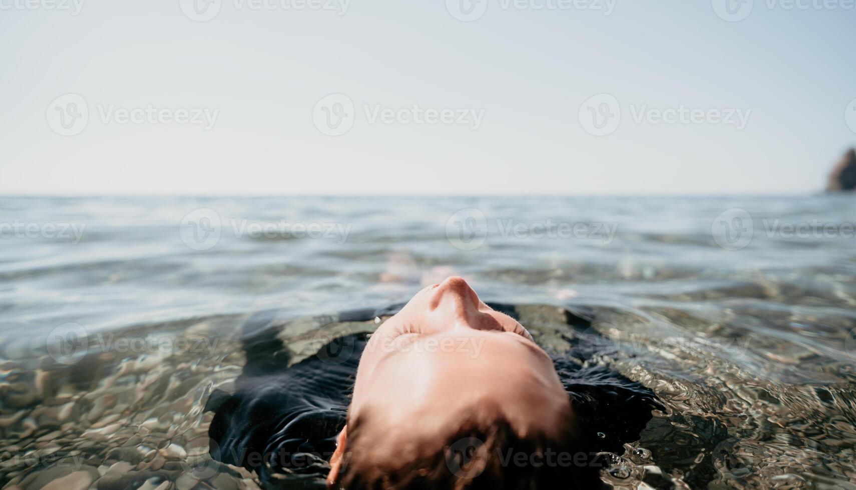 Woman swimming in sea at sunset, float on calm water back view. Concept of body image and fitness, enjoying a serene beach. Happy woman with perfect fit body enjoys sea beach photo
