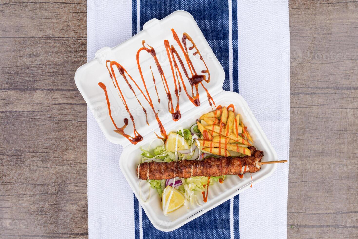 Chicken skewers on a plate with sauces and salad. Table view photo