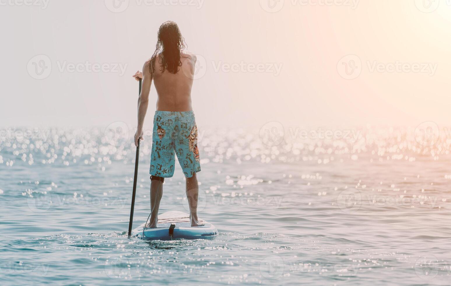 Man Sup Sea. Strong athletic man learns to paddle sup standing on board in open sea ocean on sunny day. Summer holiday vacation and travel concept. Aerial view. Slow motion photo