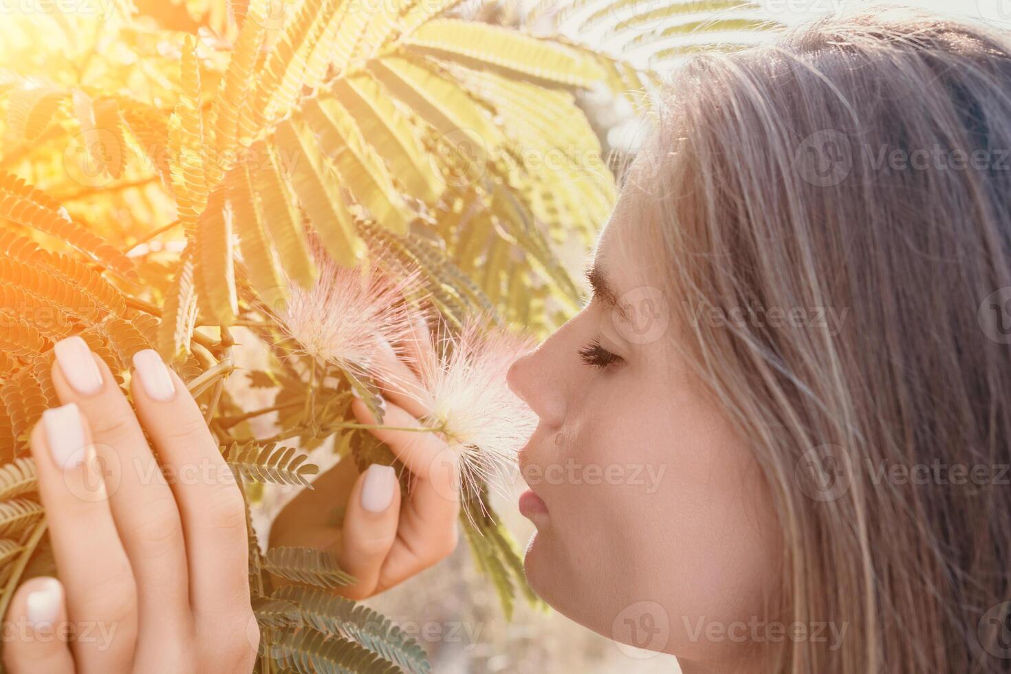 Beauty portrait of happy woman closeup. Young girl smelling Chinese acacia pink blossoming flowers. Portrait of young woman in blooming spring, summer garden. Romantic vibe. Female and nature photo