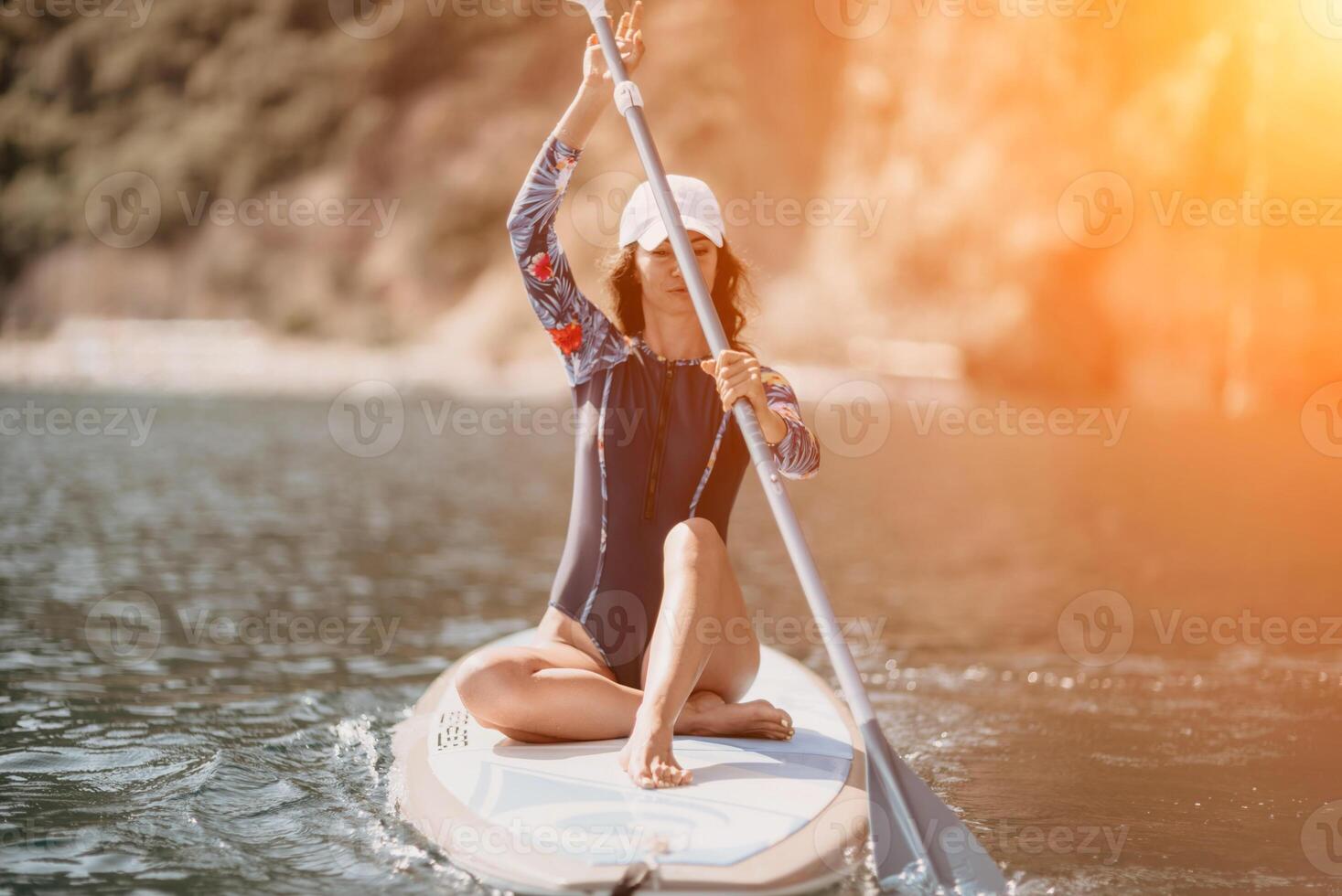 Woman sup yoga. Middle age sporty woman practising yoga pilates on paddle sup surfboard. Female stretching doing workout on sea water. Modern individual female hipster outdoor summer sport activity. photo