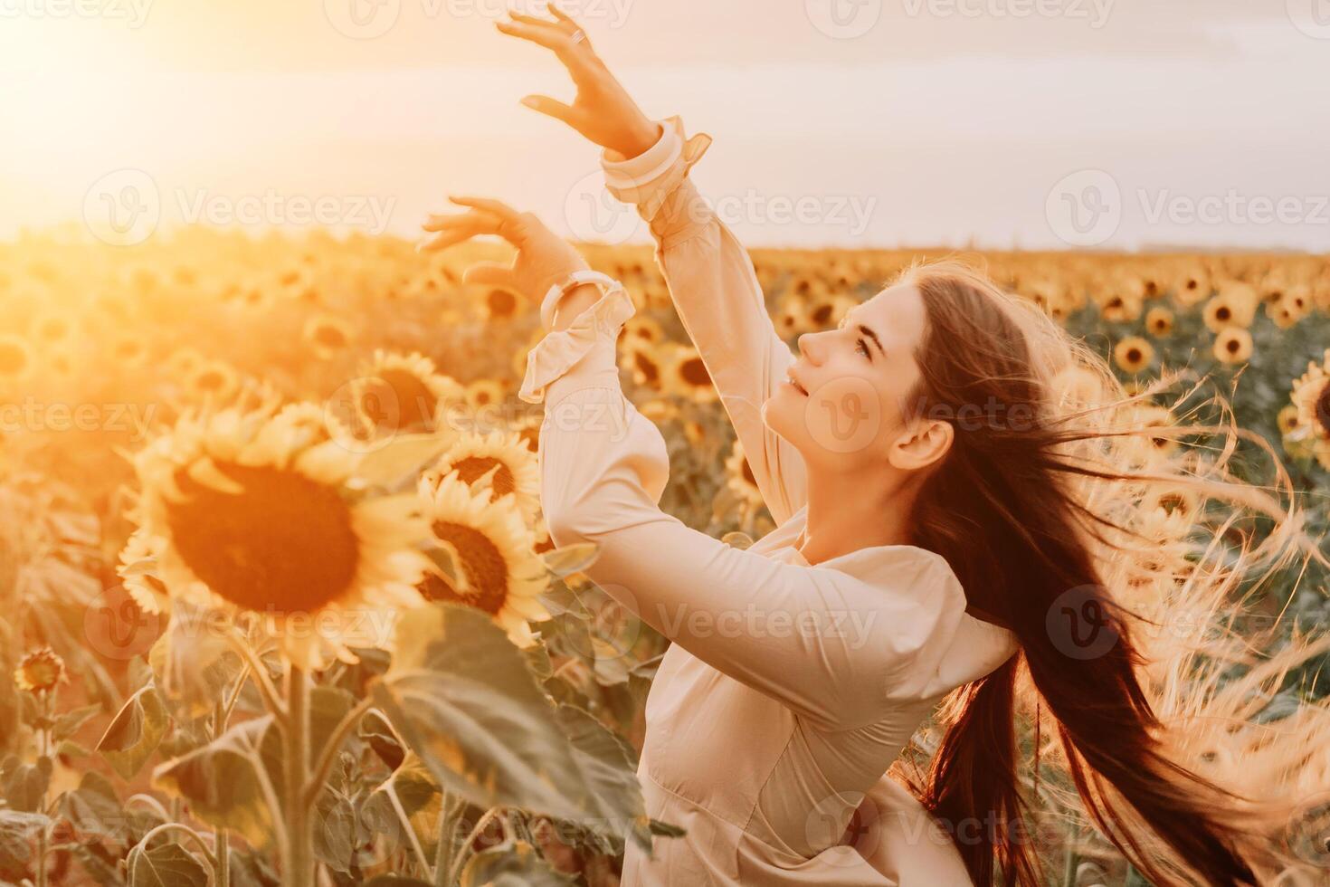 Woman in Sunflower Field. Happy girl in a straw hat posing in a vast field of sunflowers at sunset, enjoy taking picture outdoors for memories. Summer time. photo