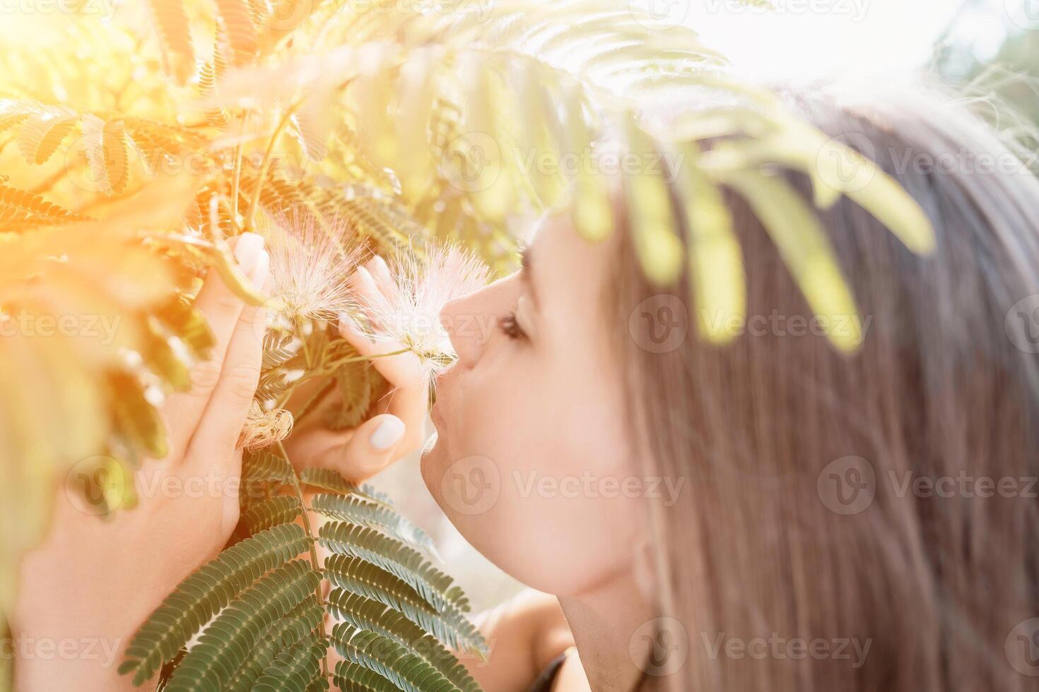 Beauty portrait of happy woman closeup. Young girl smelling Chinese acacia pink blossoming flowers. Portrait of young woman in blooming spring, summer garden. Romantic vibe. Female and nature photo
