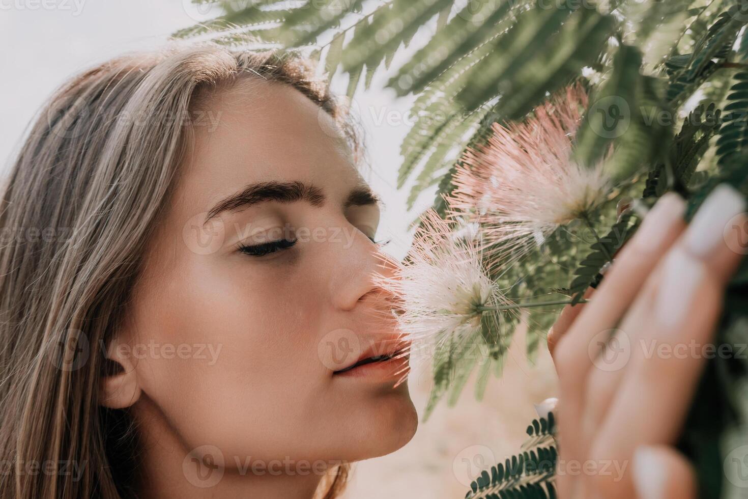 Beauty portrait of happy woman closeup. Young girl smelling Chinese acacia pink blossoming flowers. Portrait of young woman in blooming spring, summer garden. Romantic vibe. Female and nature photo