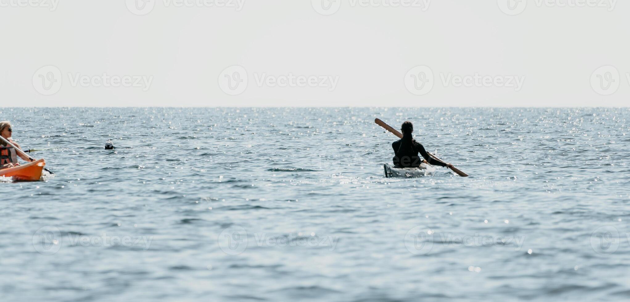 Woman sea kayak. Happy smiling woman in kayak on ocean, paddling with wooden oar. Calm sea water and horizon in background. Active lifestyle at sea. Summer vacation. photo
