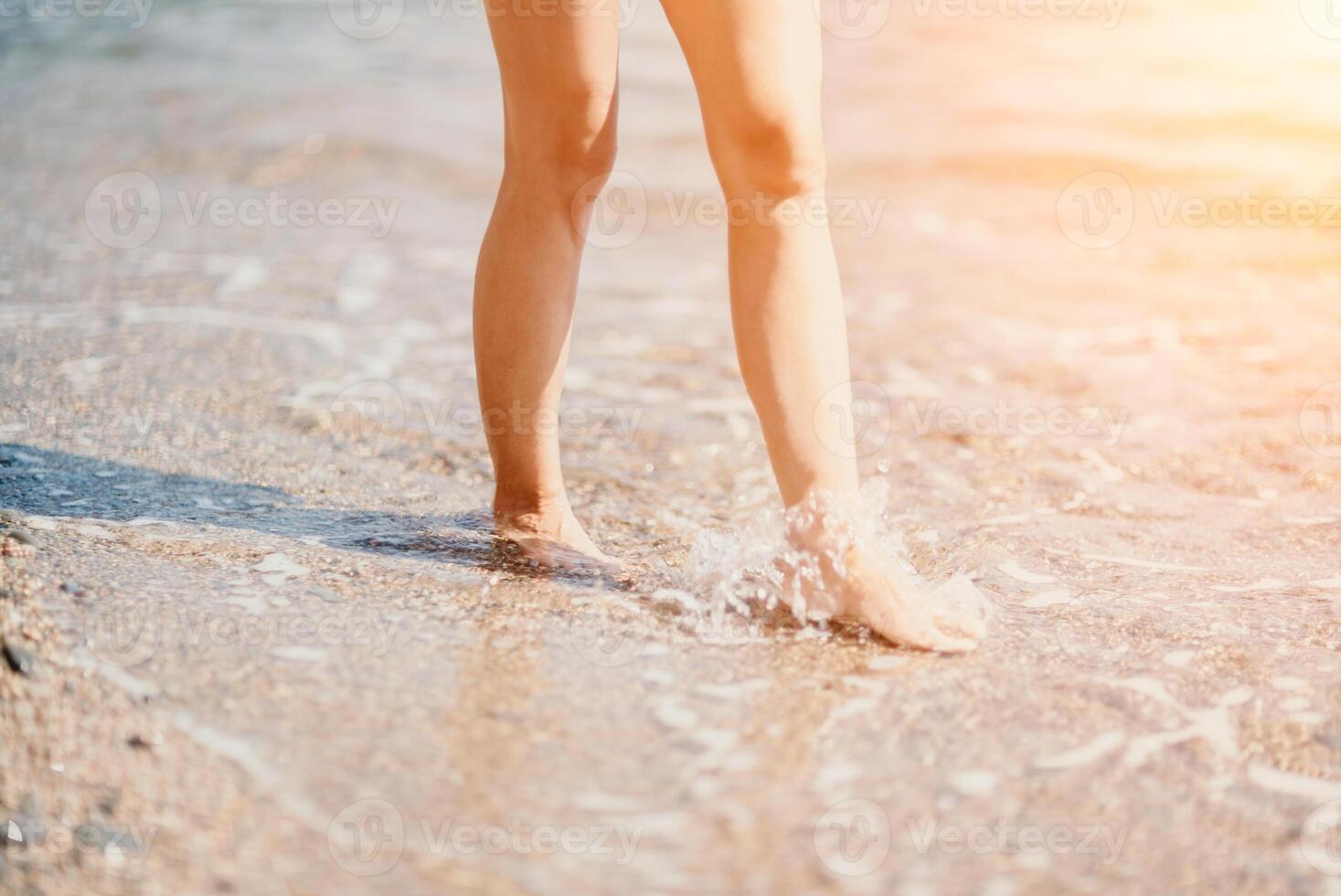 A woman walks along the beach, legs close-up. Barefoot woman sta photo