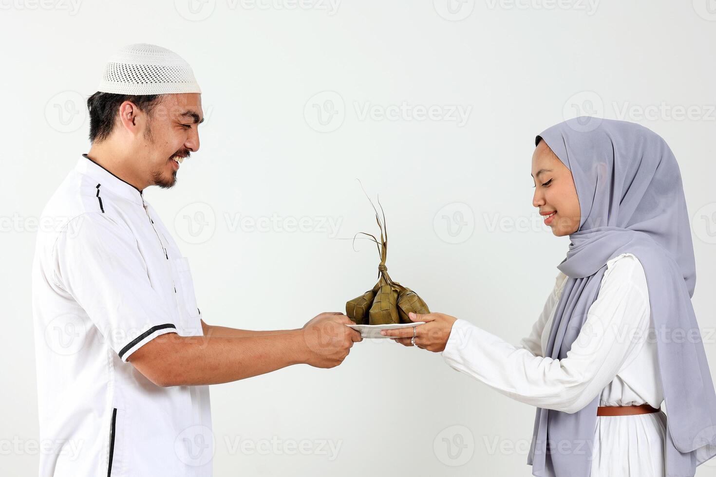 Asian MUslim Female and Male Holding White Plate with Ketupat for Eid Mubarak Celebration photo