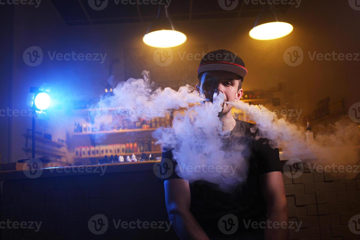 Vaping man holding a mod. A cloud of vapor at the vape shop. photo