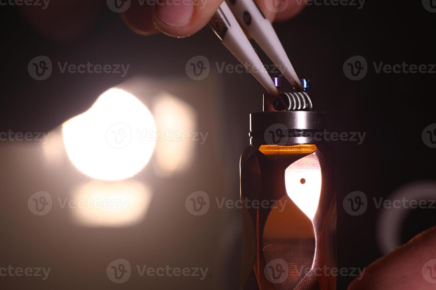 test burning the new dual coils on the atomizers deck base of electronic cigarette for vaping, close up scene photo