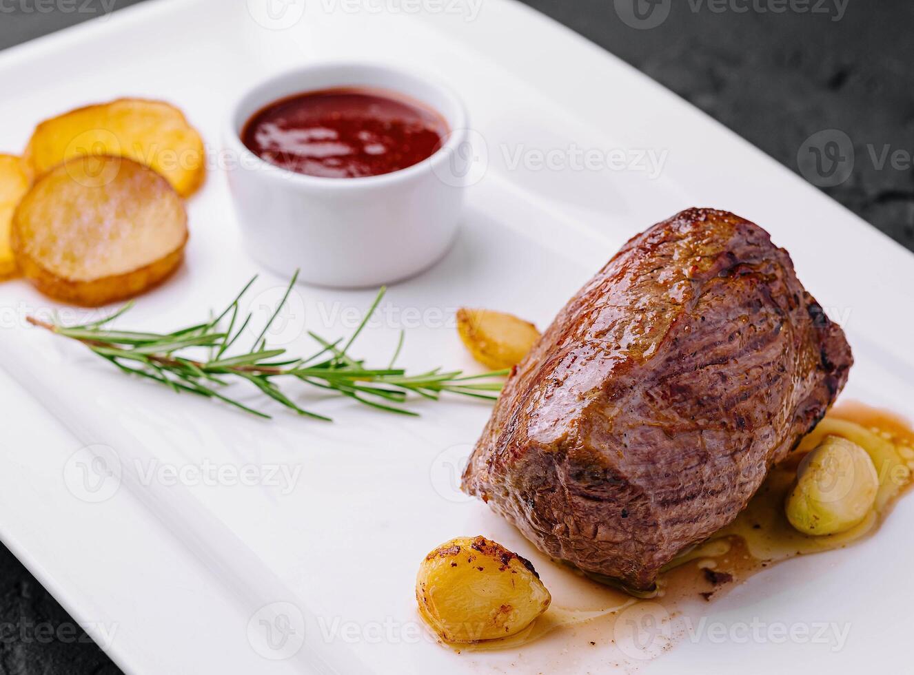 fried medallion with garlic, potatoes and rosemary photo