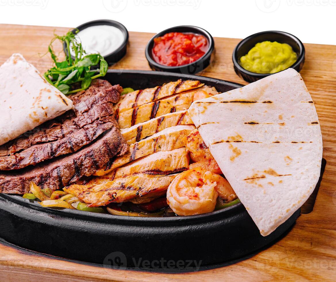 Beef chicken and shrimp fajitas on a iron cast sizzling plate photo