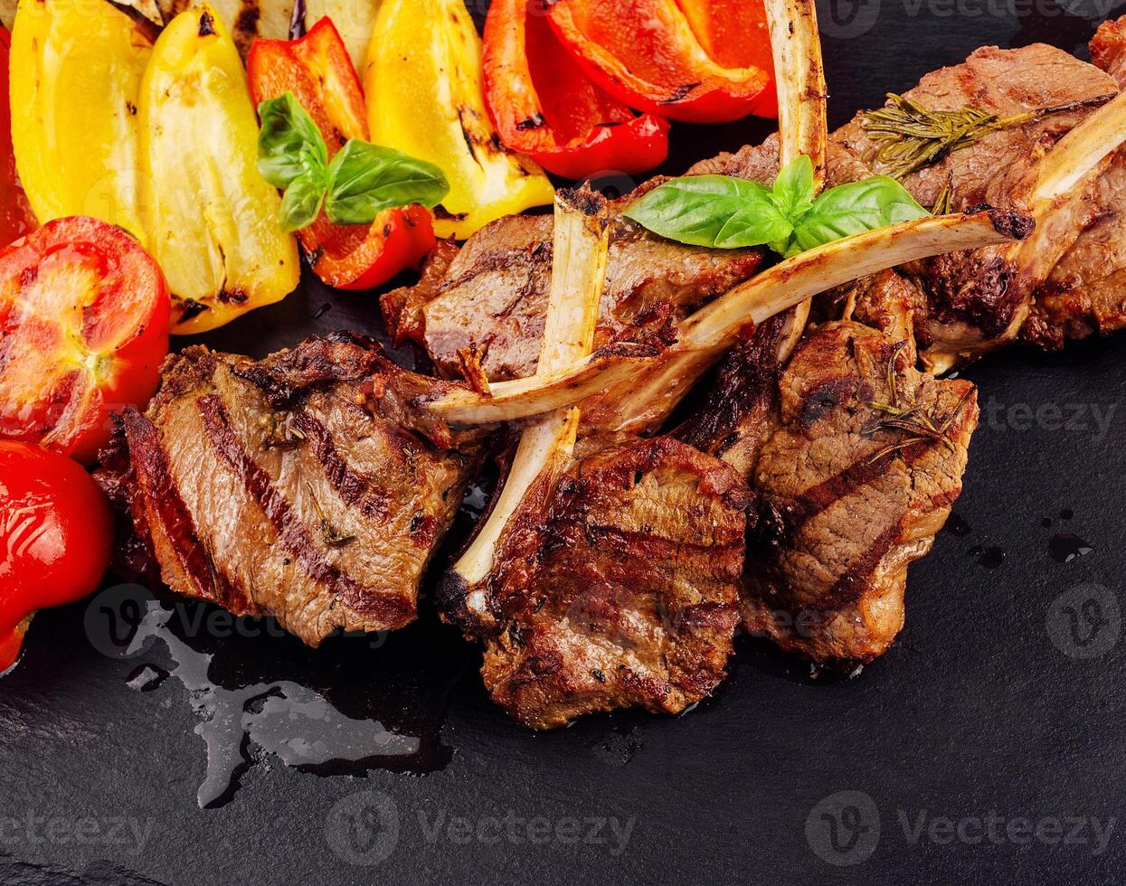 Grilled lamb chops with vegetables on a stone board photo