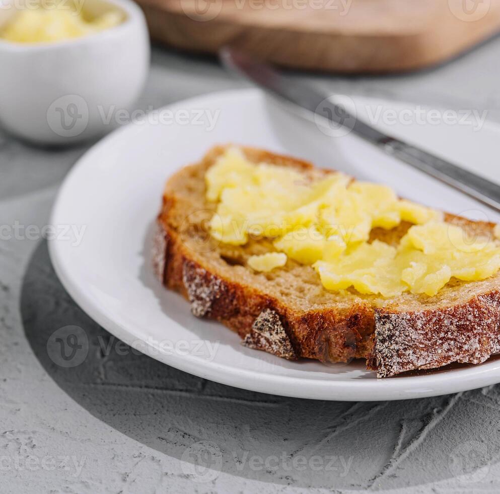 A knife spreading melted butter on bread photo