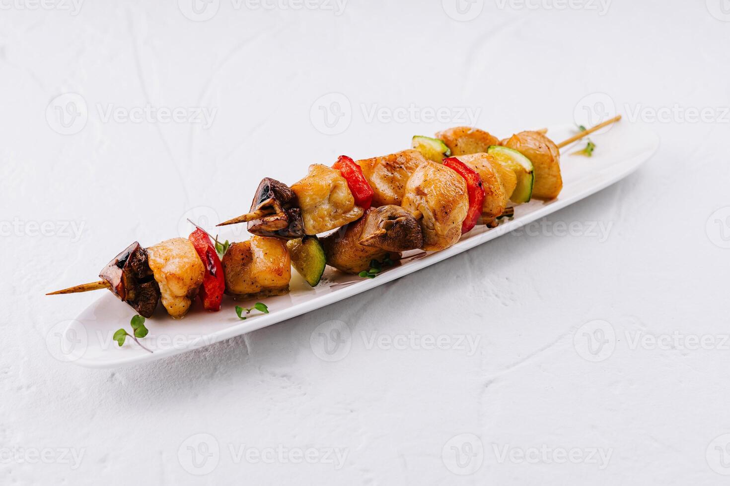 Grilled chicken skewers with vegetables on white plate photo