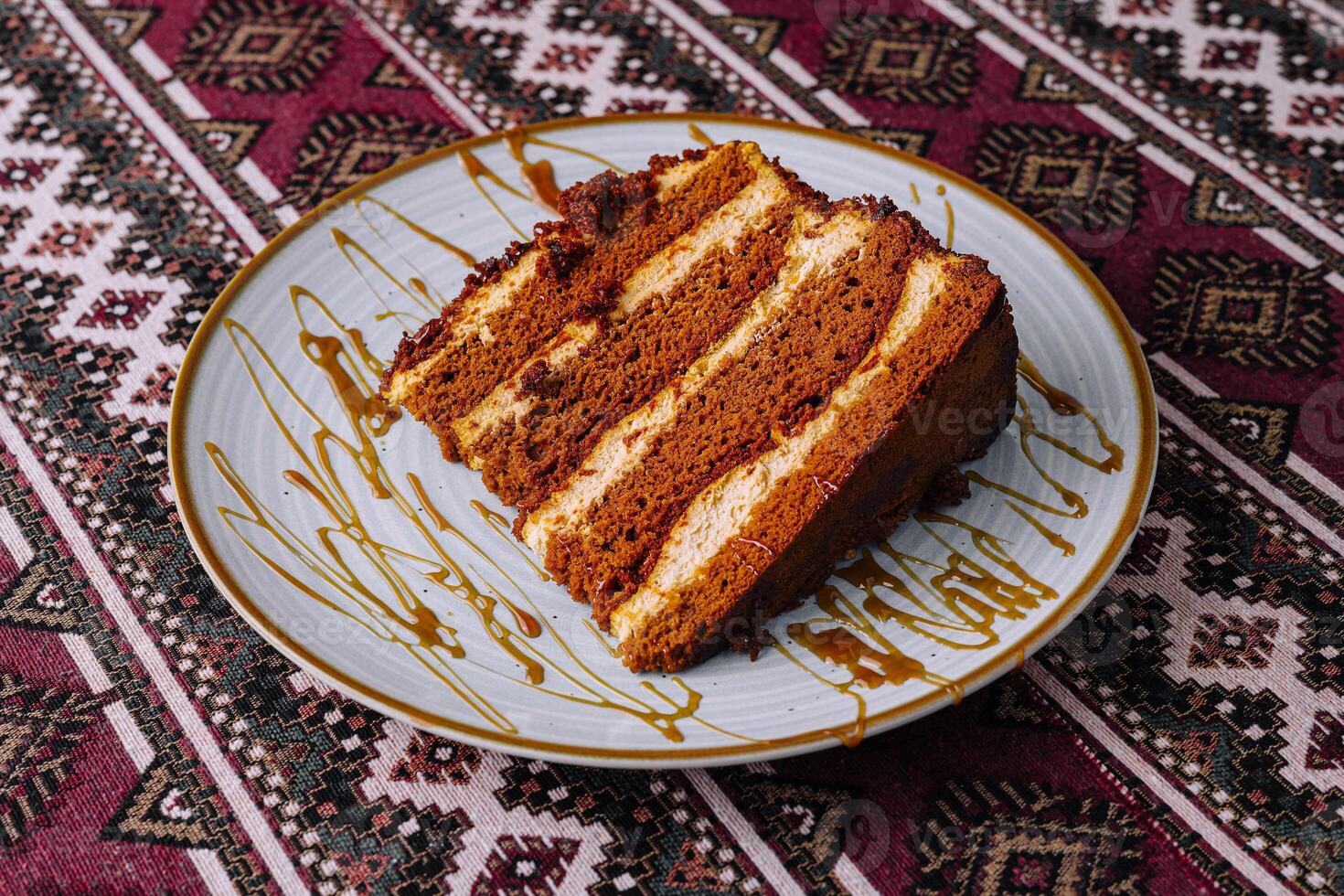 Delectable honey drizzled cake slice on patterned tablecloth photo