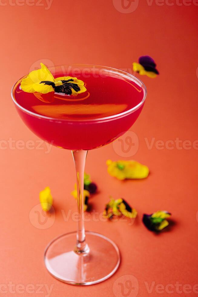 Elegant cocktail with edible flowers on warm background photo