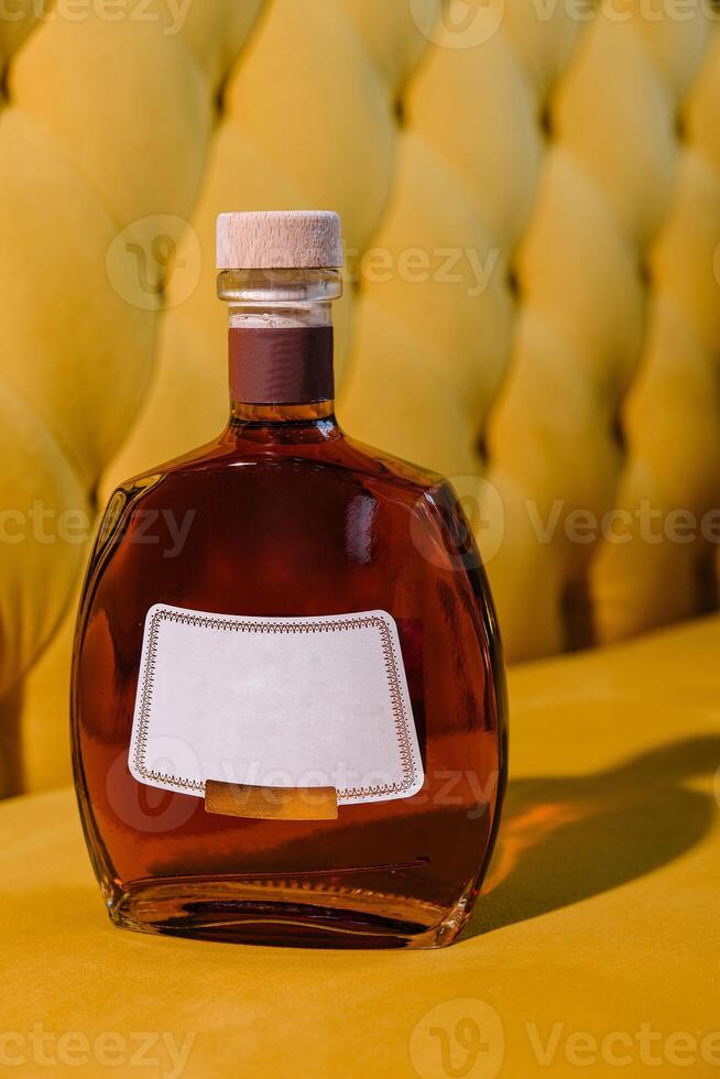 elite cognac or brandy bottle on yellow textured background photo