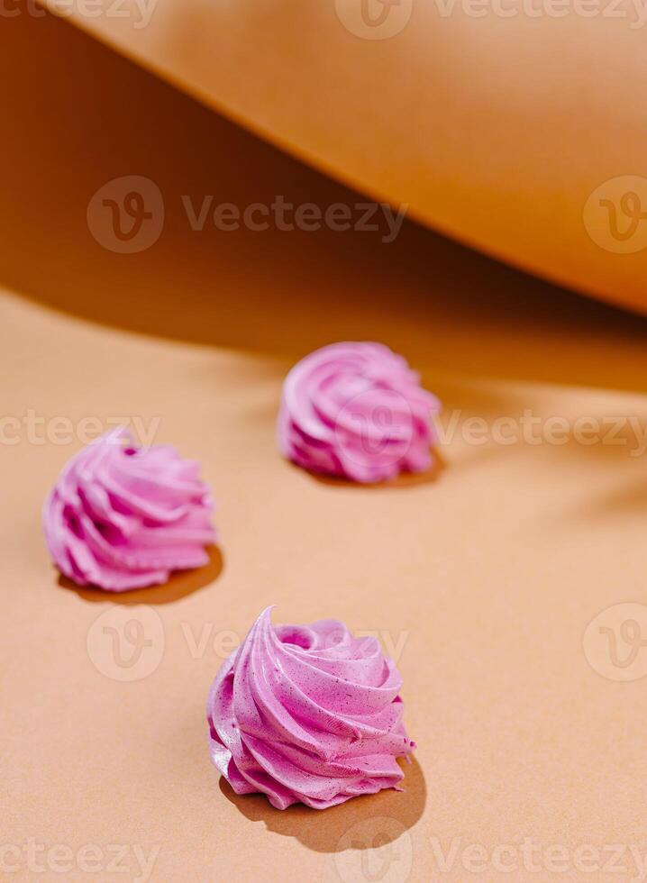 Pastel pink meringue swirls on peach background photo