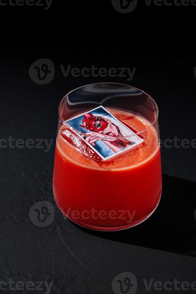 Elegant red cocktail with ice cube on dark background photo