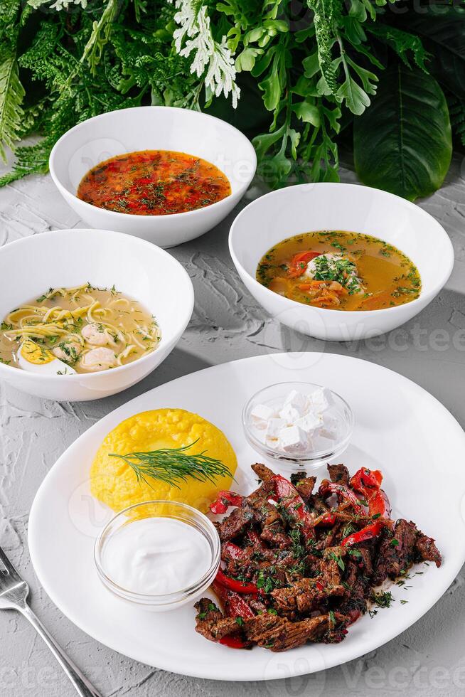 Assorted traditional soups and grilled meat dish on white table photo