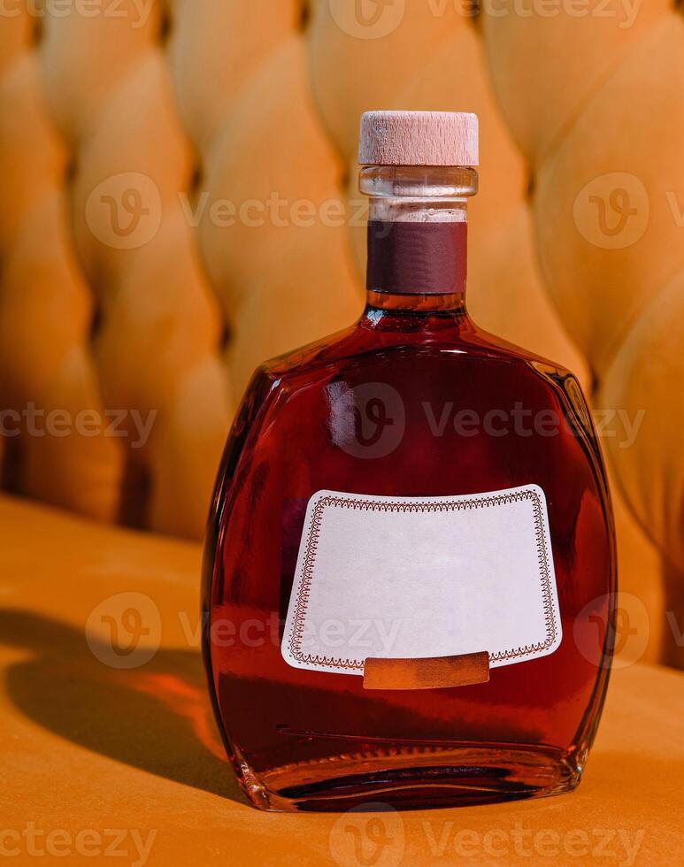 elite cognac or brandy bottle on yellow textured background photo