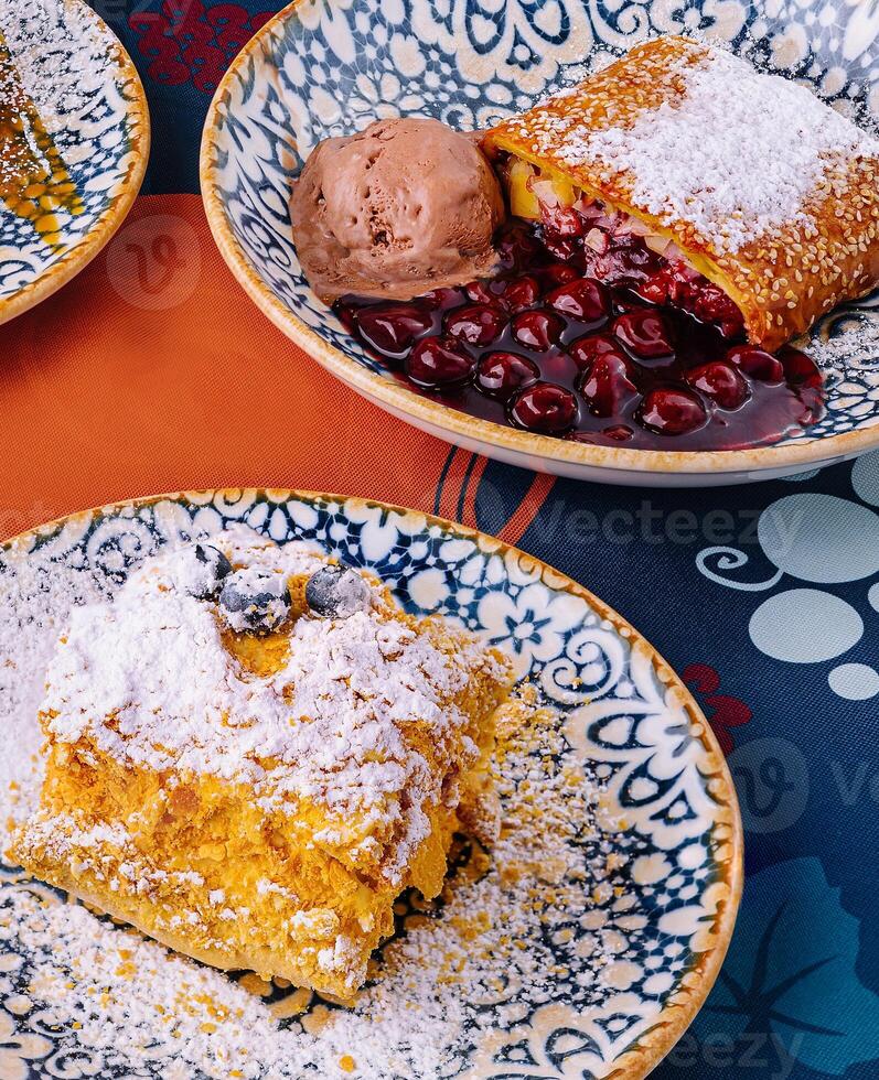 Assorted desserts with ice cream on a colorful tablecloth photo