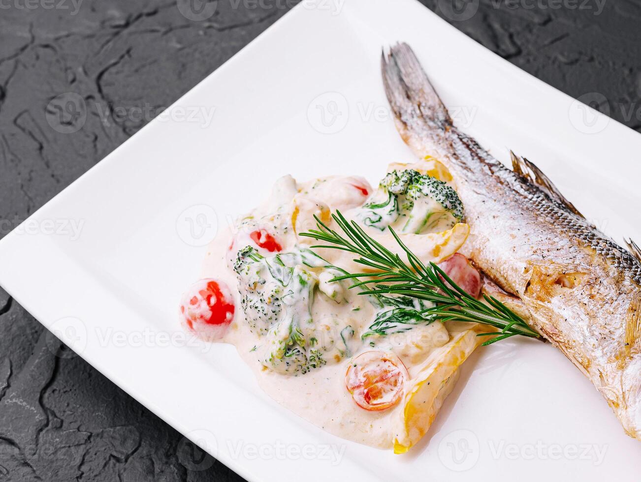 fish with broccoli and sauce on a white plate photo