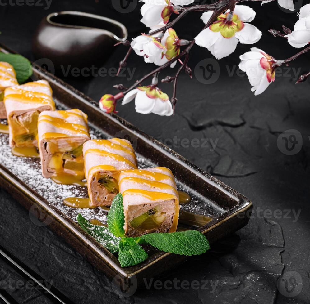 Exquisite sushi roll with kiwi and banana platter with blossoms photo