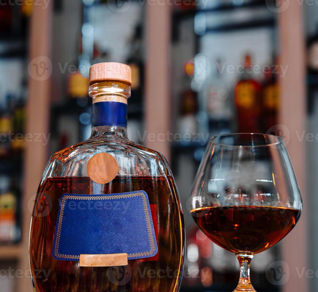 Elegant brandy bottle and glass on bar counter photo