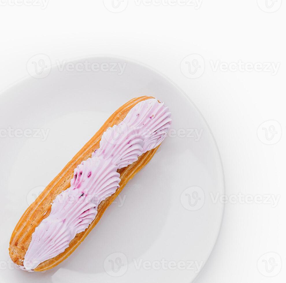 Pink iced eclair on white plate photo