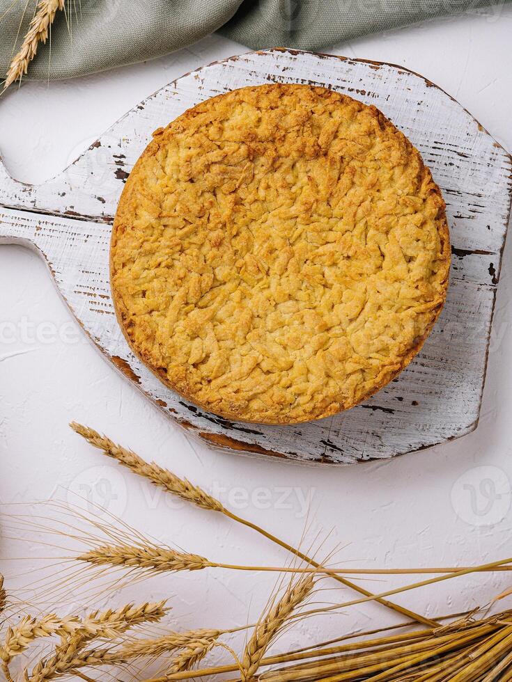 Homemade apple pie on rustic cutting board with wheat decor photo