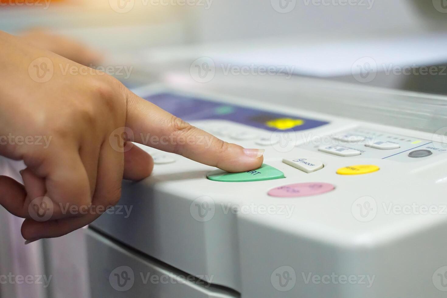 The office secretary presses the button to start the document copying machine to have another copy of the document stored in a file as evidence. . photo