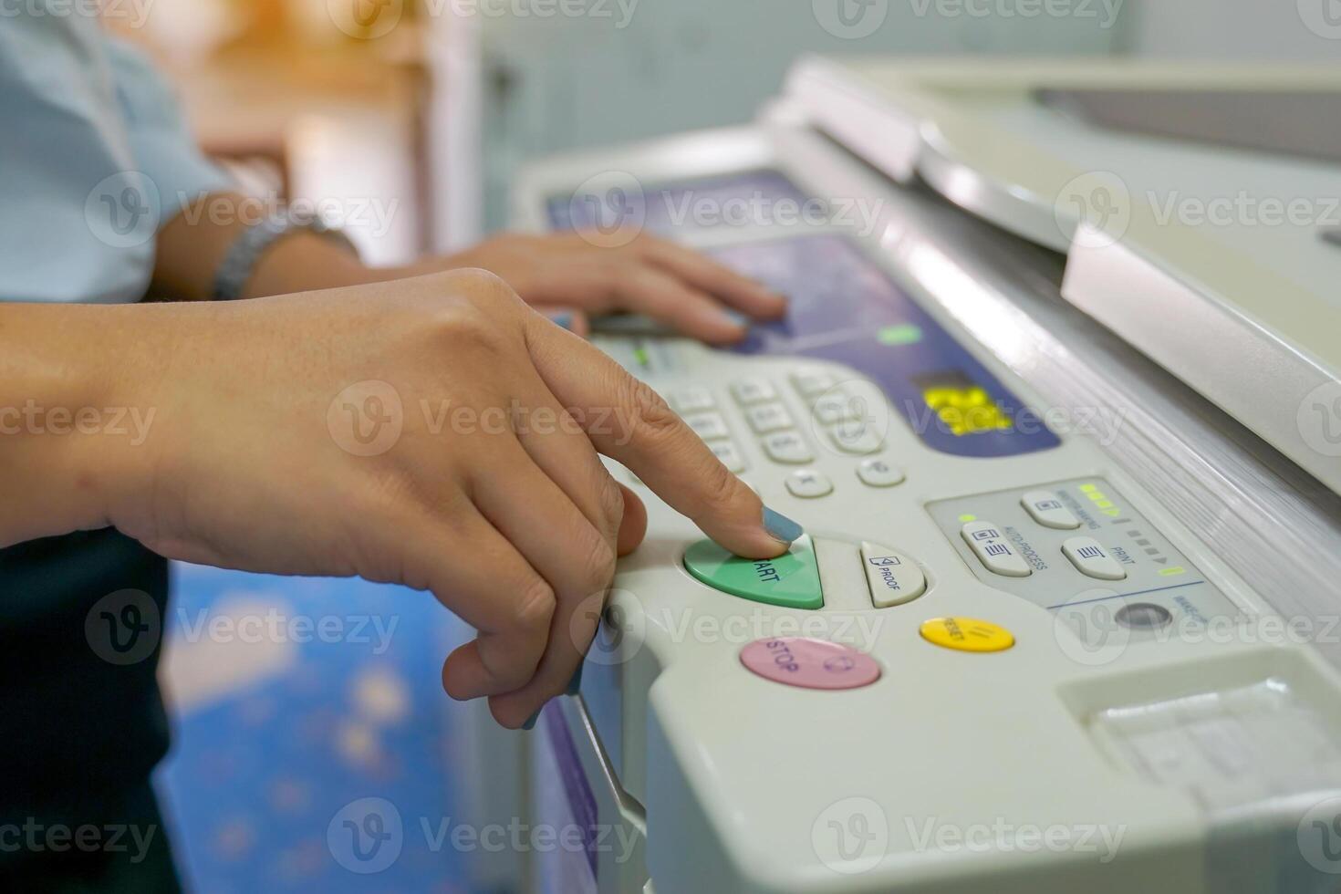 The office secretary presses the button to start the document copying machine to have another copy of the document stored in a file as evidence. photo