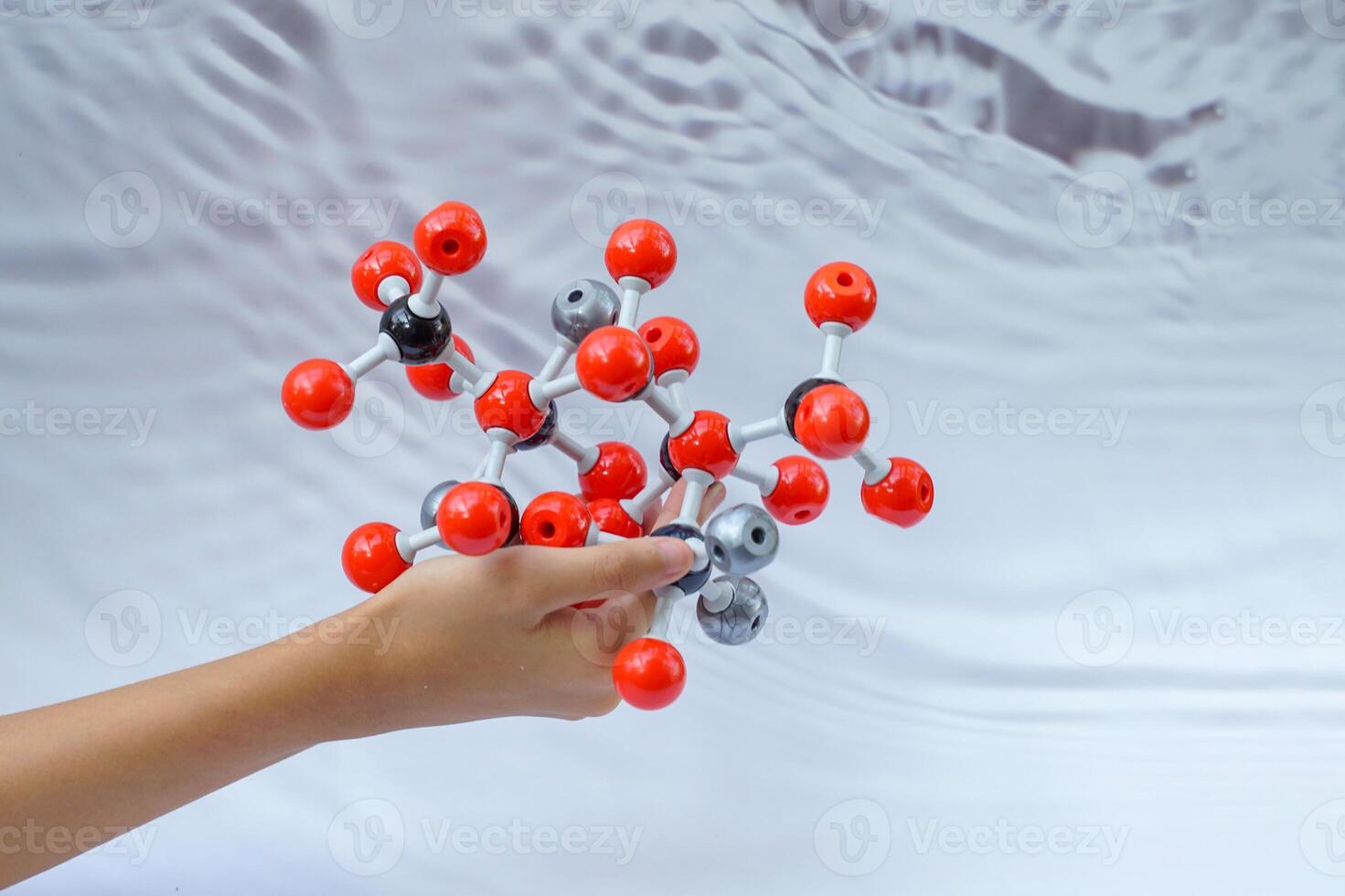 Hand holding a Simulate Shape of covalent molecules on a gray and white background. photo