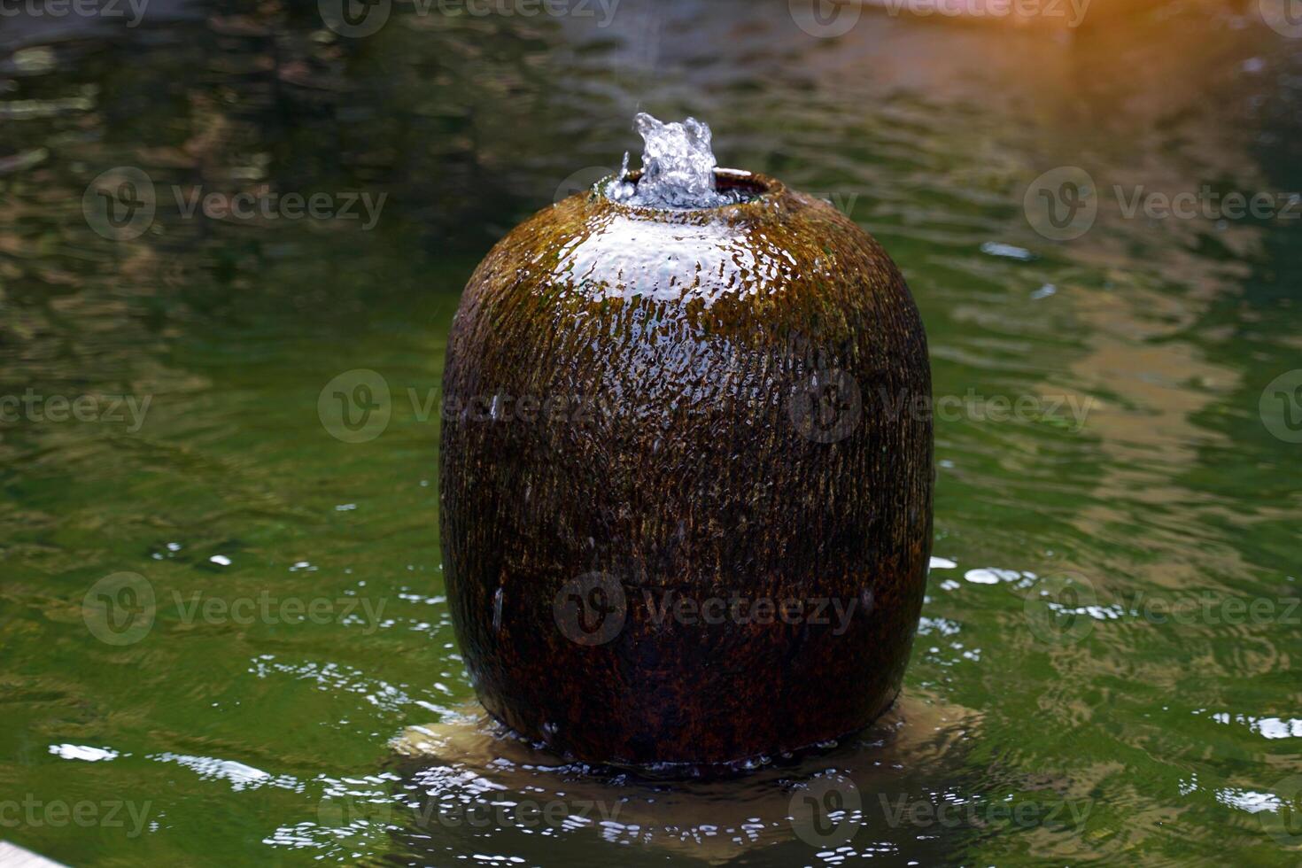 Ceramic fountain jar installed at the pond in the garden of the house. It is pottery for decorating houses and gardens to be beautiful, shady, natural and enhance feng shui. photo