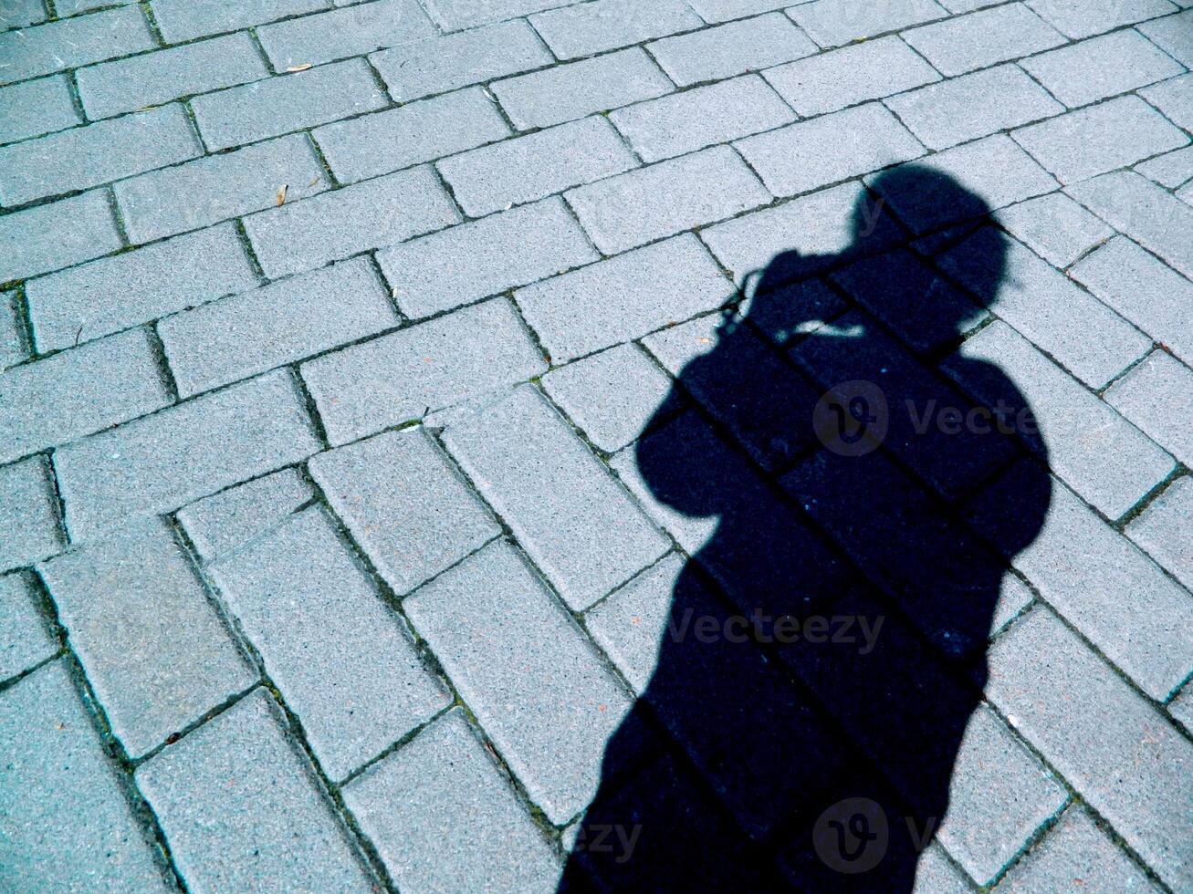 silhouette shadow of a girl with a camera on the background of road masonry photo