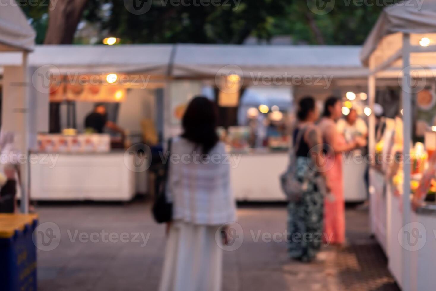 abstract blurred festival food market night light bokeh background. People walking travel street food and stalls photo