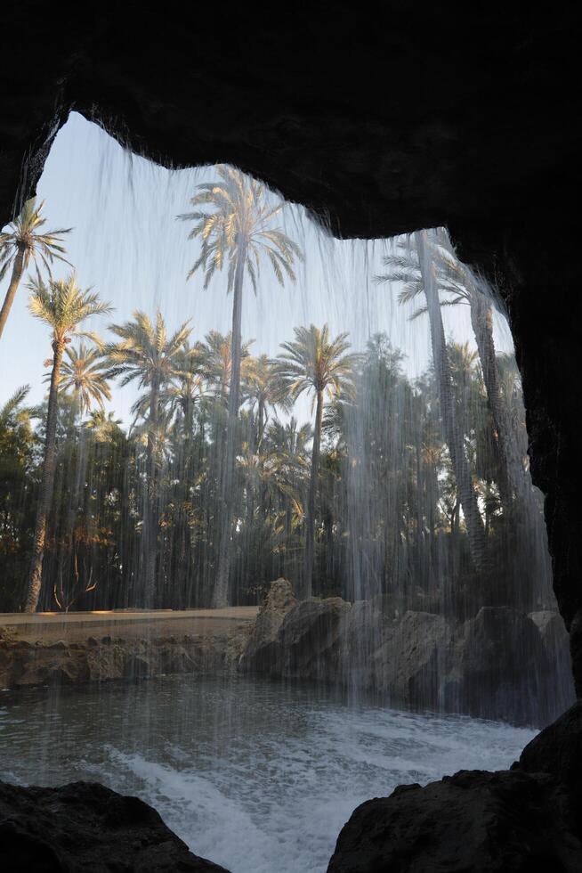 look through a whole in the rocks through the waterfall on the trees photo
