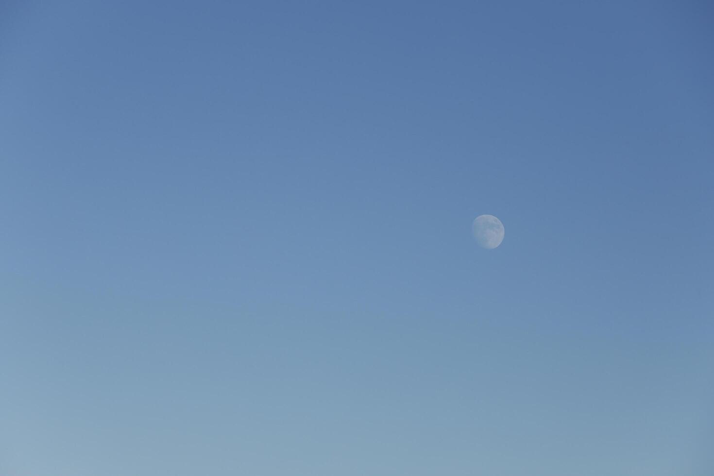 moon shines in a bright blue sky photo