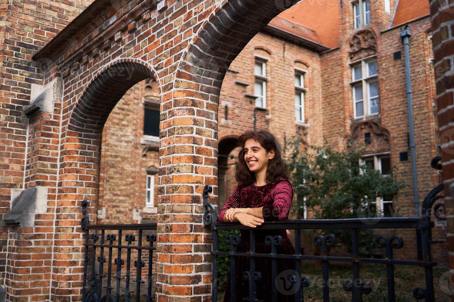 a girl in a red corduroy dress with an open back walks through the streets of Bruges on an autumn day photo