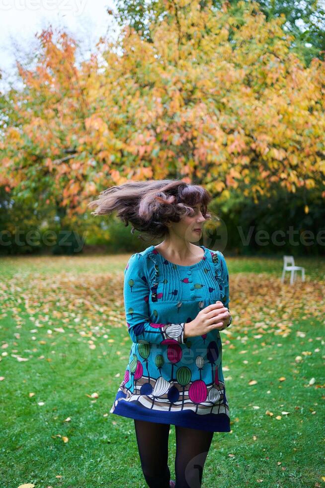 a girl in a dress with balloons is playing in the autumn garden photo